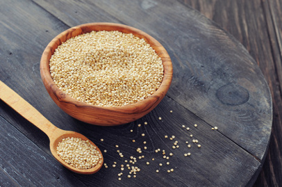 Raw quinoa seeds in the wooden bowl on wooden background closeup