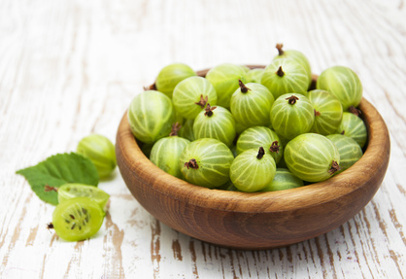 Gooseberry with leaves on a wooden background